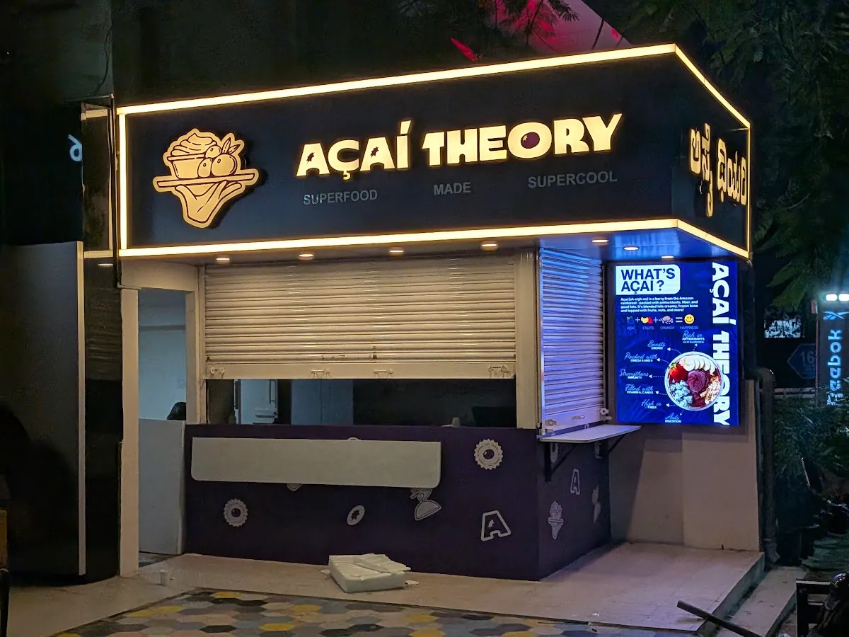 Açaí Theory storefront in Indiranagar at night with the shutters down and the PixelSpot outdoor LED wall showing a What's açaí slide